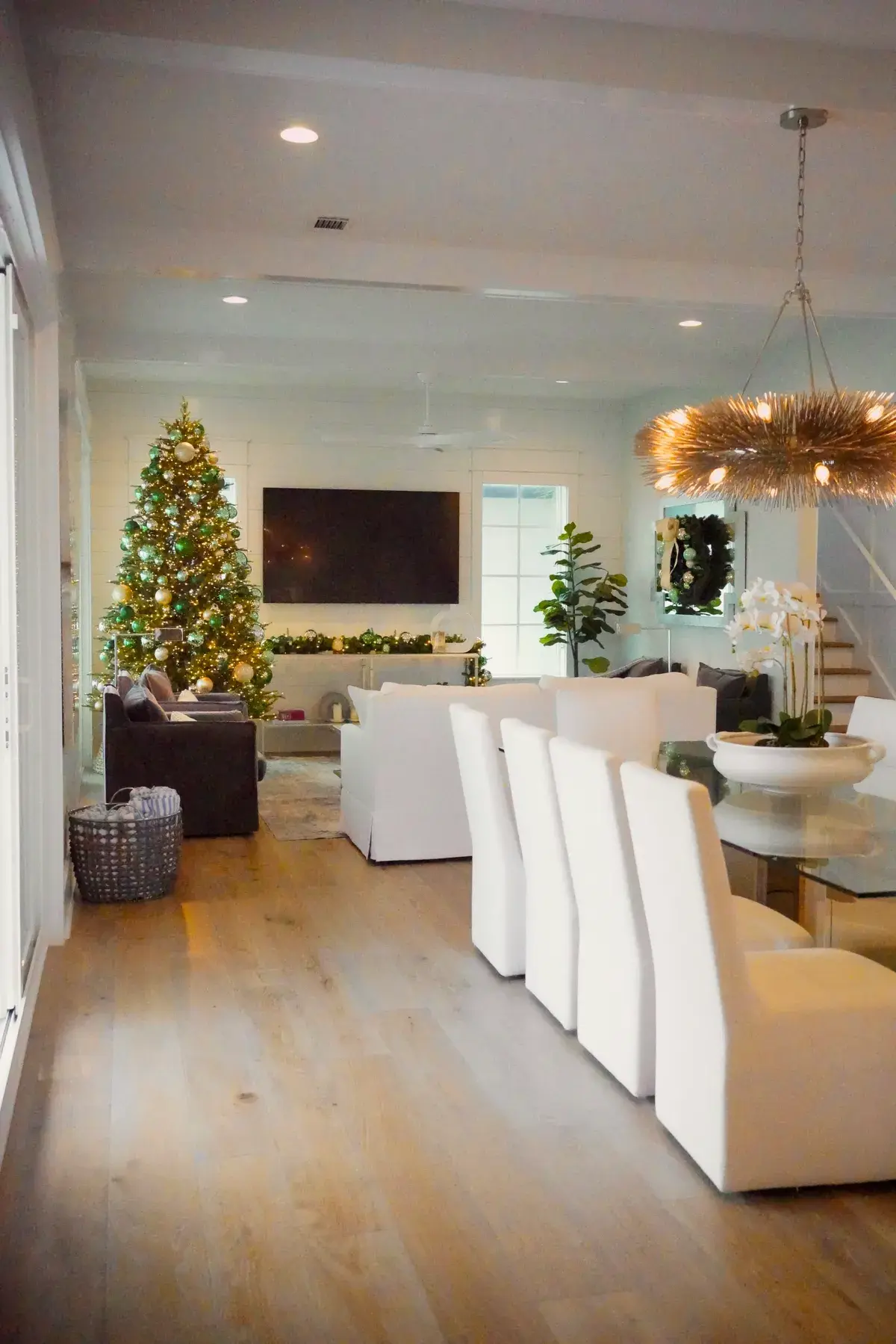 An open living and dining room with a lit Christmas tree