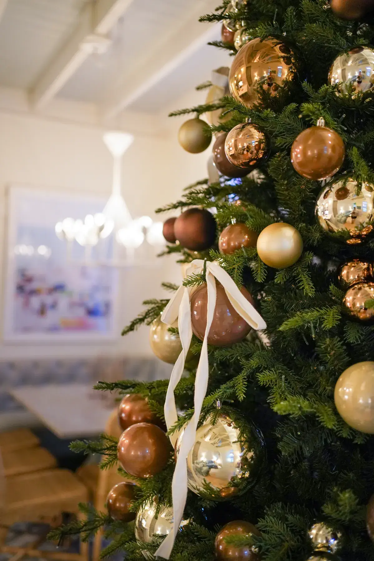 Gold and copper ornaments with a ribbon on a Christmas tree