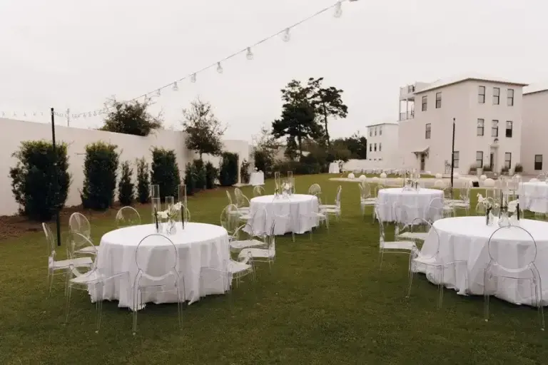 Reception tables dressed in white linen on the lawn at dusk