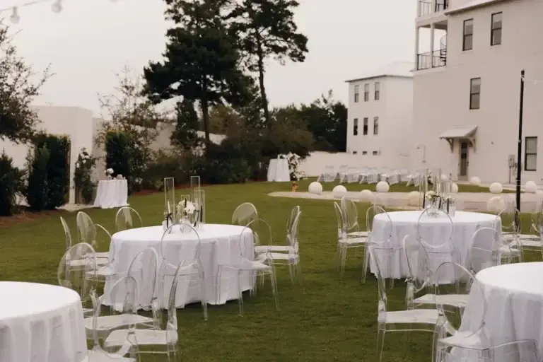 Round tables and ghost chairs under string lights
