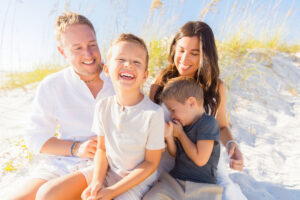 family smiling on 30A beach at sunset during photography session